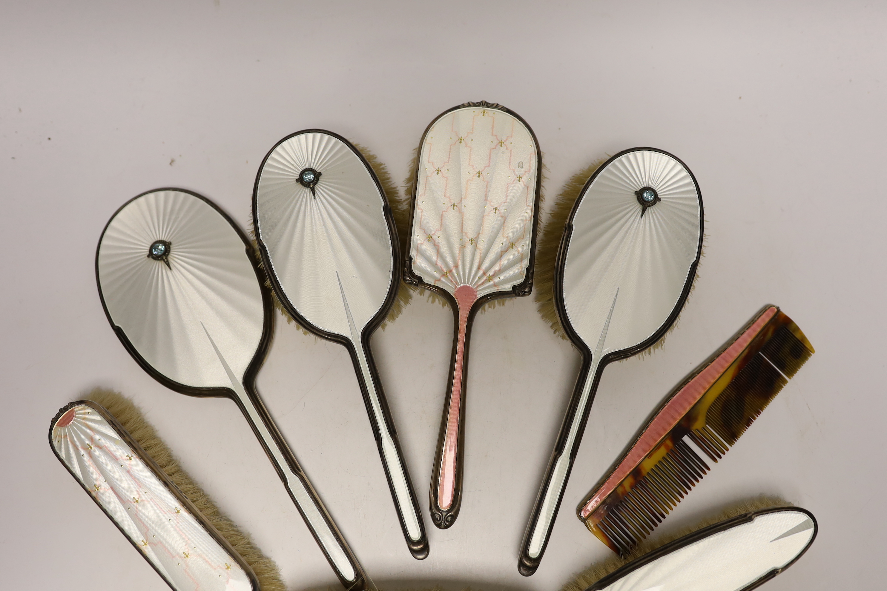 A George VI Art Deco silver, guilloche enamel, blue zircon and marcasite set five piece mirror and brush set and similar enamelled comb, Albert Carter, Birmingham, 1936/7, together with three other later silver and ename